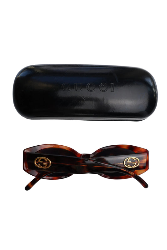 Gucci GG Logo Sunglasses — Sunglasses folded beside their black case