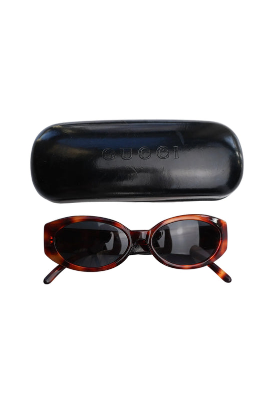 Gucci GG Logo Sunglasses — Front view of the sunglasses beside their case