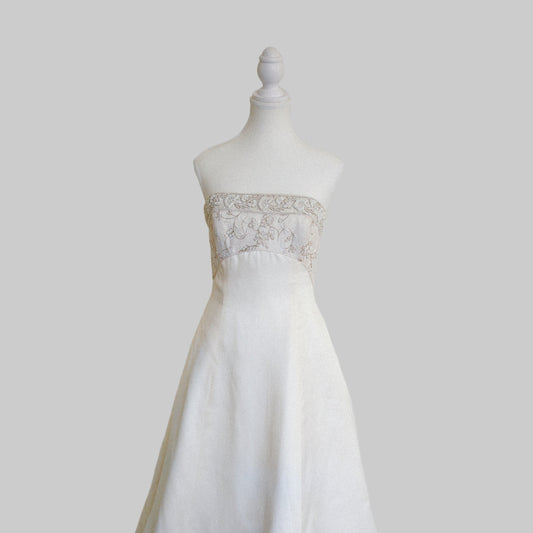 White wedding dress on a mannequin against a plain white wall.